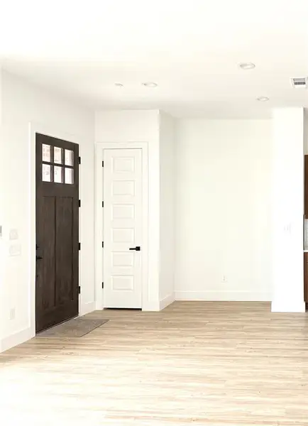 Foyer entrance with light wood finished floors and recessed lighting