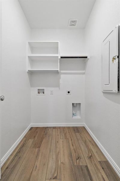 Clothes washing area with hardwood / wood-style floors, hookup for a washing machine, and hookup for an electric dryer