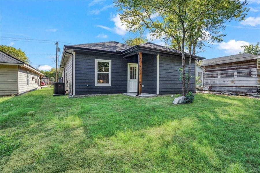 Back of house featuring a lawn and cooling unit