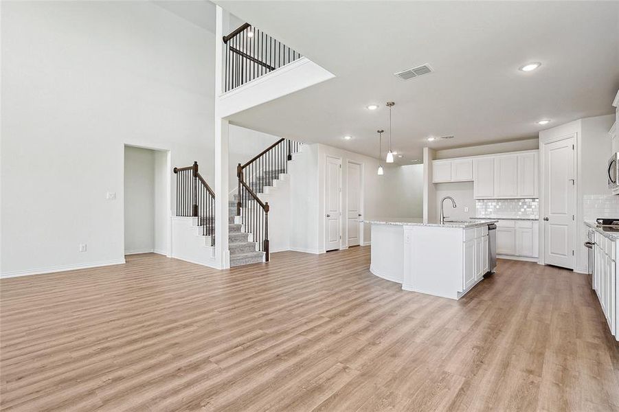 Kitchen featuring white cabinets, a kitchen island with sink, light hardwood / wood-style floors, and decorative backsplash