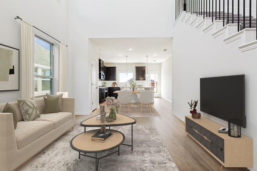 Living area featuring light wood-style floors, a towering ceiling, baseboards, and recessed lighting Living area featuring light wood-style floors, a towering ceiling, baseboards, and recessed lighting