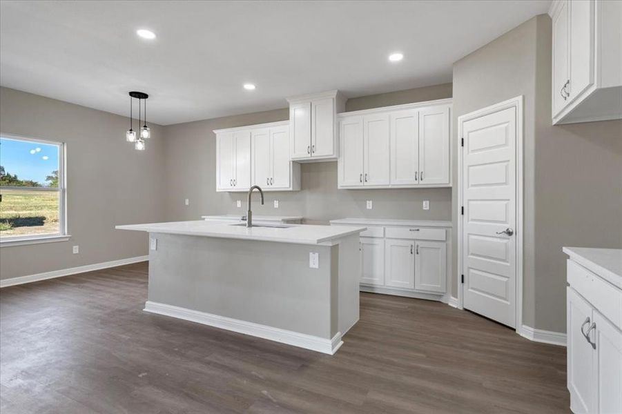Kitchen featuring recessed lighting, hanging light fixtures, white cabinetry, dark wood finished floors, and an island with sink