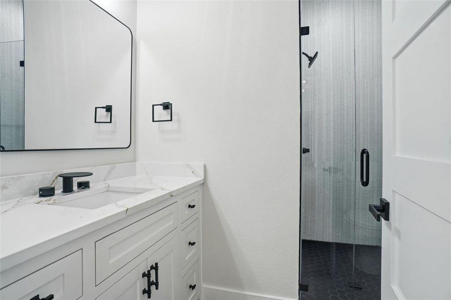 Full hallway bathroom featuring a quartz vanity and a walk-in shower with modern tile finishes.