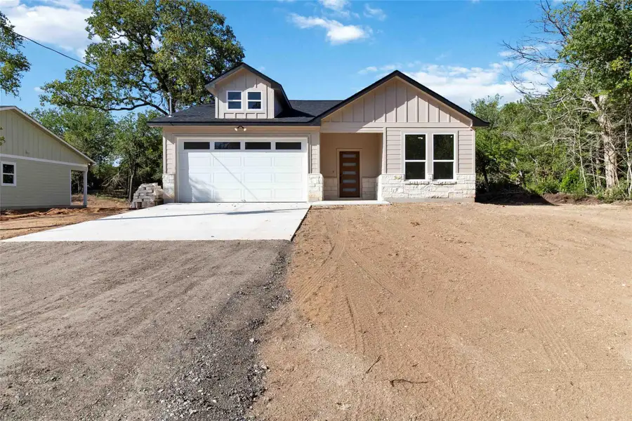 View of front facade with stone siding, driveway, and board and batten siding View of front facade with stone siding, driveway, and board and batten siding