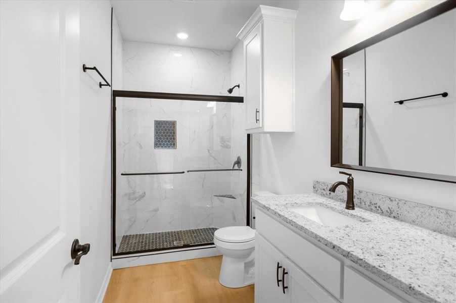 Full bathroom with vanity, a marble finish shower, and light wood finished floors