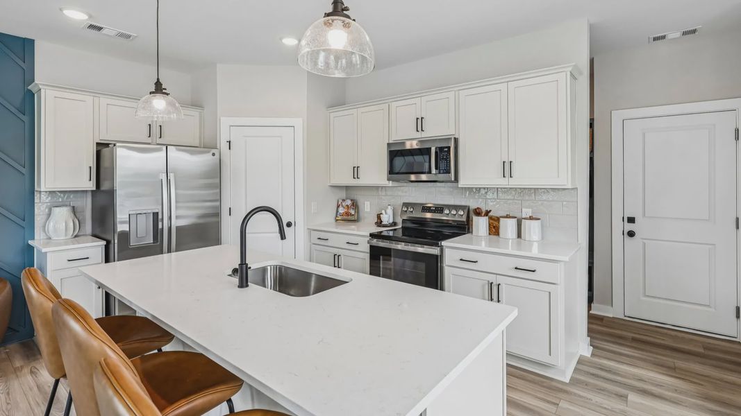 View of kitchen with quartz countertops, tile backsplash, and pendant lighting