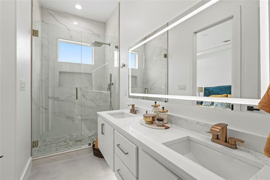 Full bath featuring a sink, a marble finish shower, and double vanity