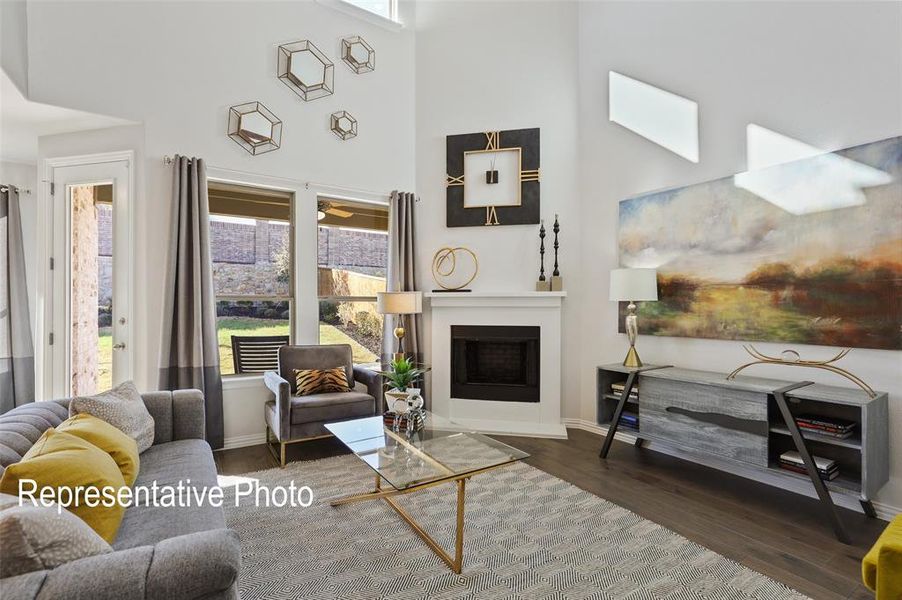 Living area featuring a white fireplace with a black firebox, high ceilings, dark wood-finish flooring, and multiple windows offering views of the exterior