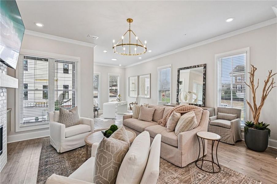 Living area featuring hardwood / wood-style floors, plenty of natural light, a glass covered fireplace, ornamental molding, and recessed lighting