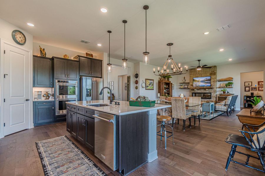 Kitchen featuring dark wood-style floors, light countertops, appliances with stainless steel finishes, open floor plan, and a kitchen bar