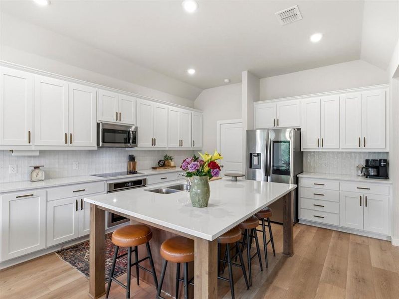 Farmhouse-inspired kitchen with ample cabinetry, generous counter space, and open sightlines to living area.