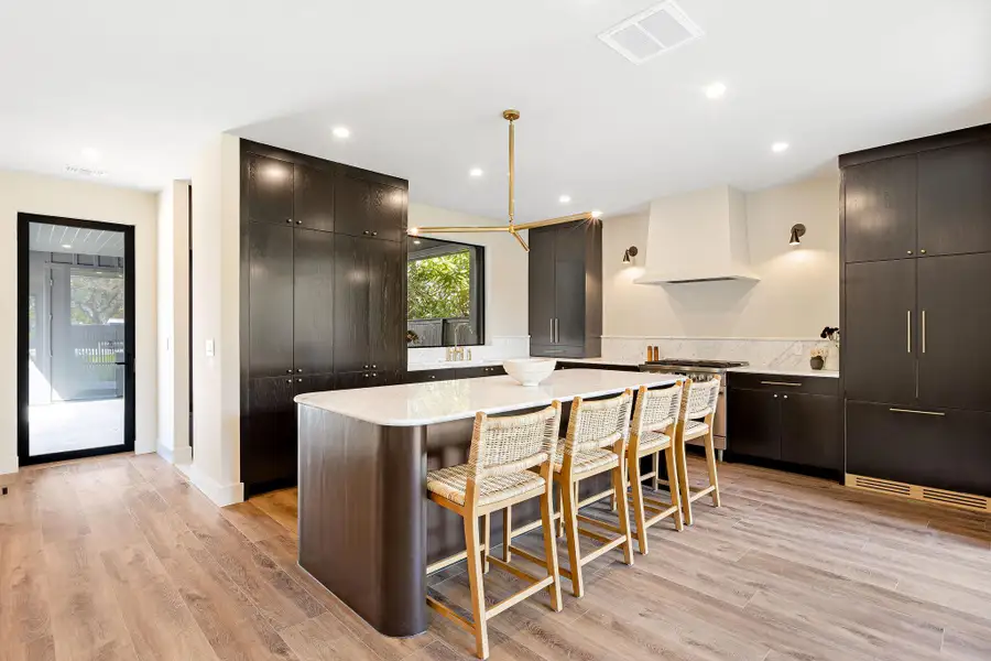 Kitchen with light stone counters, a breakfast bar, a center island, light wood-style floors, and recessed lighting Kitchen with light stone counters, a breakfast bar, a center island, light wood-style floors, and recessed lighting