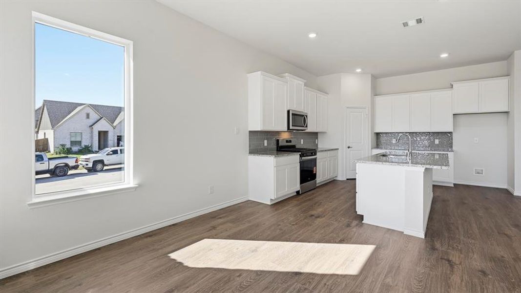 Kitchen featuring white cabinetry, decorative backsplash, appliances with stainless steel finishes, light stone counters, and dark wood-type flooring Kitchen featuring white cabinetry, decorative backsplash, appliances with stainless steel finishes, light stone counters, and dark wood-type flooring