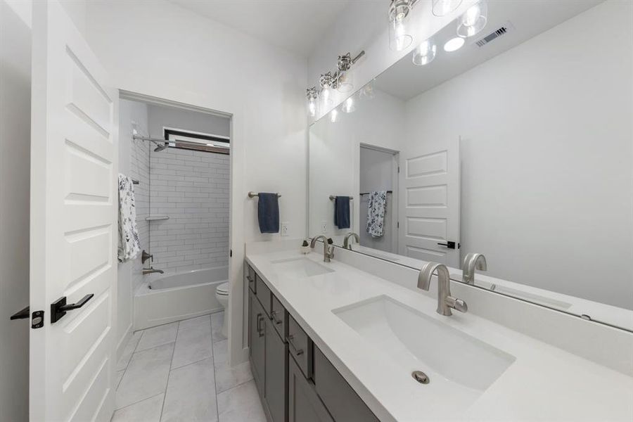 The secondary bathroom features dual sinks and a stylish tile shower/tub combo, providing both convenience and a modern aesthetic.