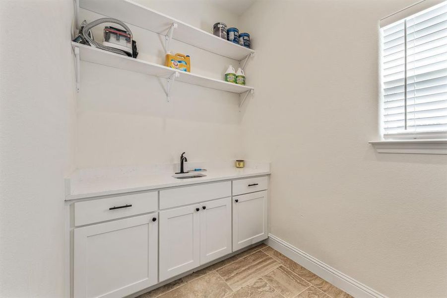 Bar area featuring white cabinetry, open shelves, and light stone countertops Bar area featuring white cabinetry, open shelves, and light stone countertops