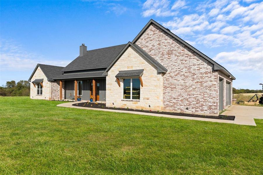Exterior featuring a blend of light-colored brick and stone, a dark gray shingle roof, and a covered porch with natural wood posts