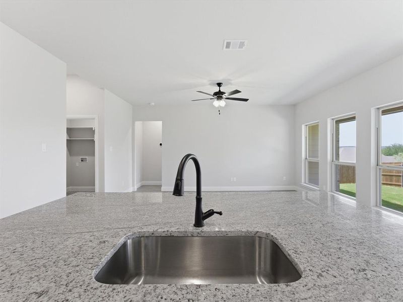 Kitchen island featuring a stainless steel undermount sink, a matte black gooseneck faucet, and light-toned speckled countertops Kitchen island featuring a stainless steel undermount sink, a matte black gooseneck faucet, and light-toned speckled countertops