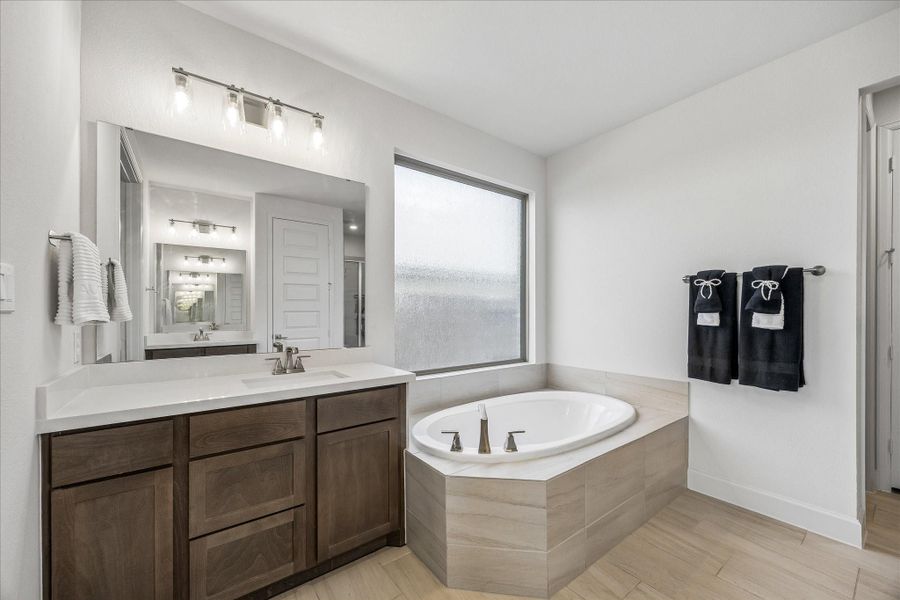 Spa-inspired primary bath featuring soaking tub, quartz vanity, and modern finishes throughout