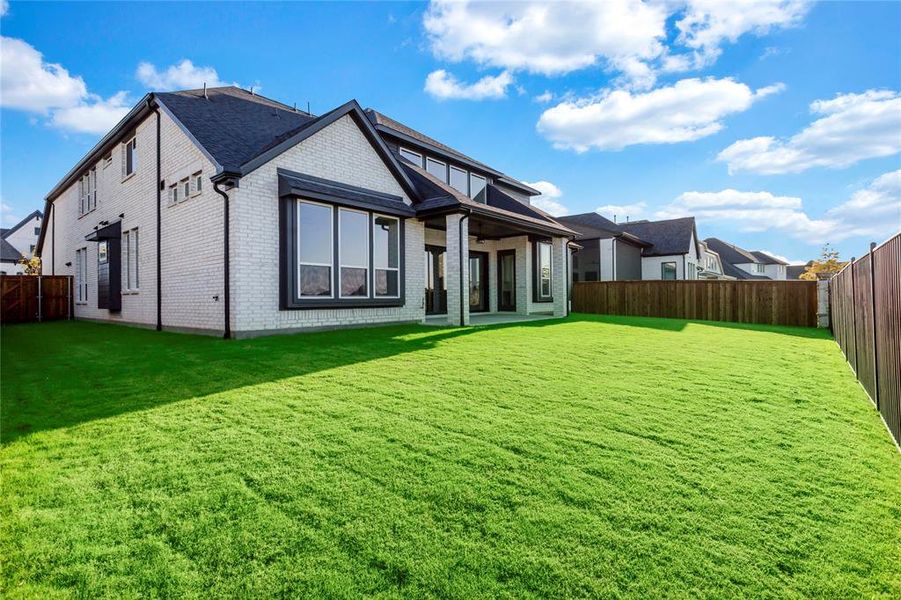 Back of house featuring brick siding, a patio, a fenced backyard, and a residential view
