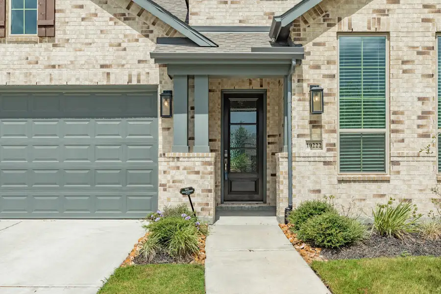 Stunning wooden and glass front door entry that creates a warm, welcoming first impression for this beautiful home.