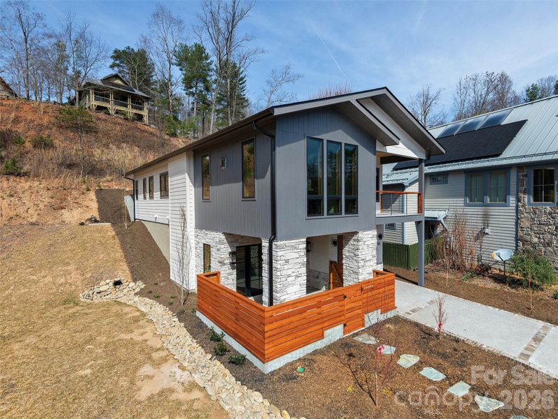 Side/front exterior view of the completed Courtyard Villa highlighting contemporary design, cement HardiePlank siding, cultured stone accents, private courtyard entry, covered porch, and low-maintenance landscaping.