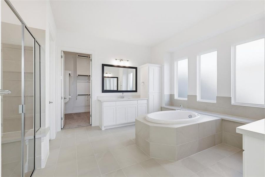 Bathroom featuring vanity, a garden tub, a spacious closet, and light tile patterned floors Bathroom featuring vanity, a garden tub, a spacious closet, and light tile patterned floors