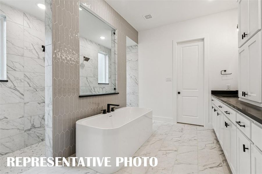 Offering a double walk through shower with free standing tub, you'll enjoy a spa like experience every day in this dream owner's bath!  REPRESENTATIVE PHOTO