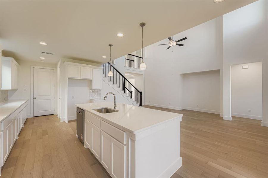 Kitchen featuring white cabinets, light wood finished floors, a kitchen island with sink, recessed lighting, and hanging light fixtures Kitchen featuring white cabinets, light wood finished floors, a kitchen island with sink, recessed lighting, and hanging light fixtures