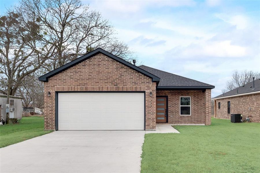 View of front of house with a garage, central AC, and a front lawn