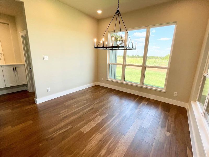 Unfurnished dining area featuring an inviting chandelier and dark hardwood / wood-style floors