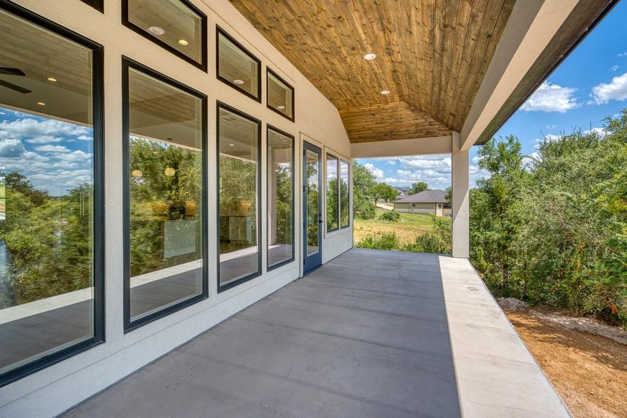 A spacious covered patio provides a serene outlook onto surrounding trees and distant homes.