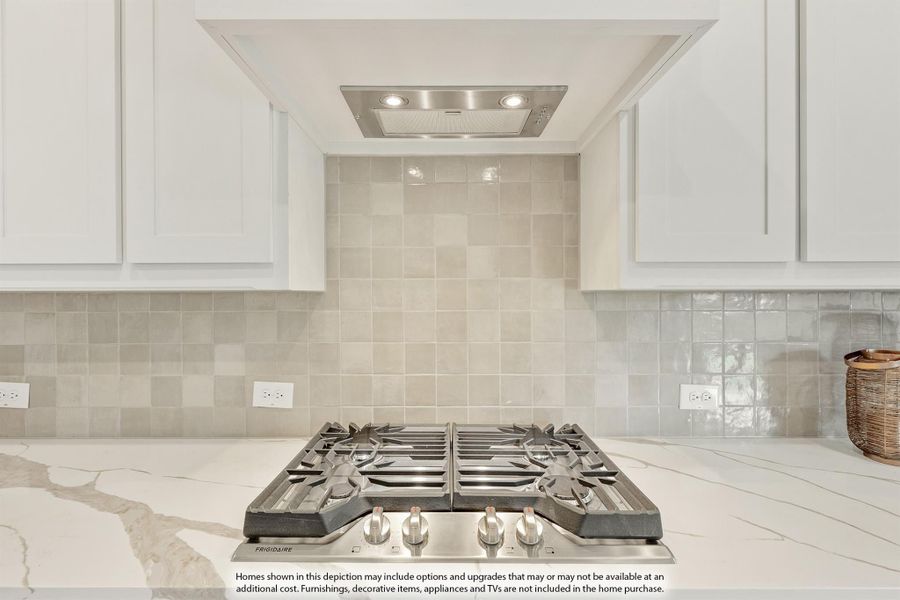 Kitchen cooktop area with stainless gas range, built-in vent hood, white cabinets, and beige tile backsplash Kitchen cooktop area with stainless gas range, built-in vent hood, white cabinets, and beige tile backsplash