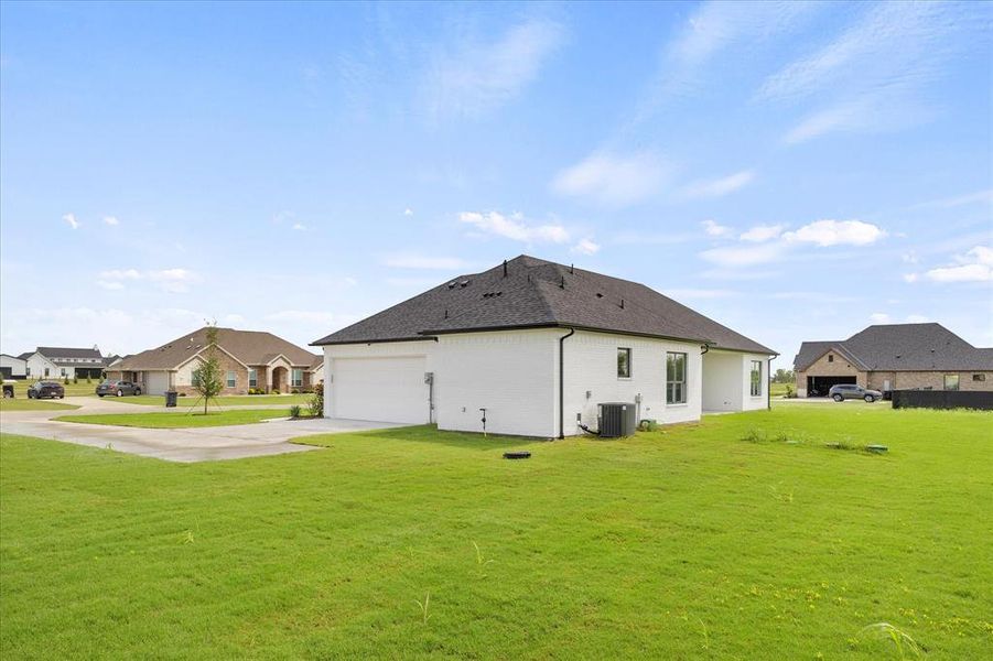 View of side of home with a lawn, cooling unit, and a garage