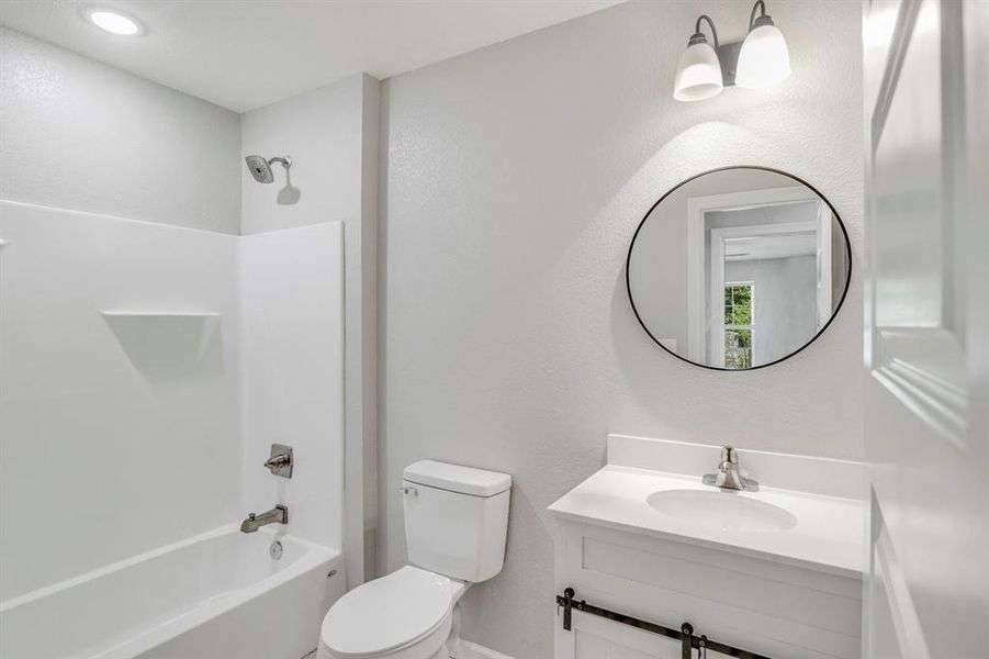 Bathroom with shower combination, vanity, and a textured wall Bathroom with shower combination, vanity, and a textured wall