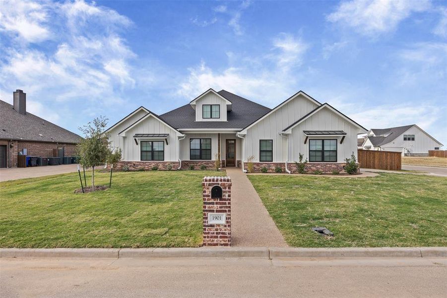 Modern farmhouse style home featuring board and batten siding, covered porch, and roof with shingles Modern farmhouse style home featuring board and batten siding, covered porch, and roof with shingles