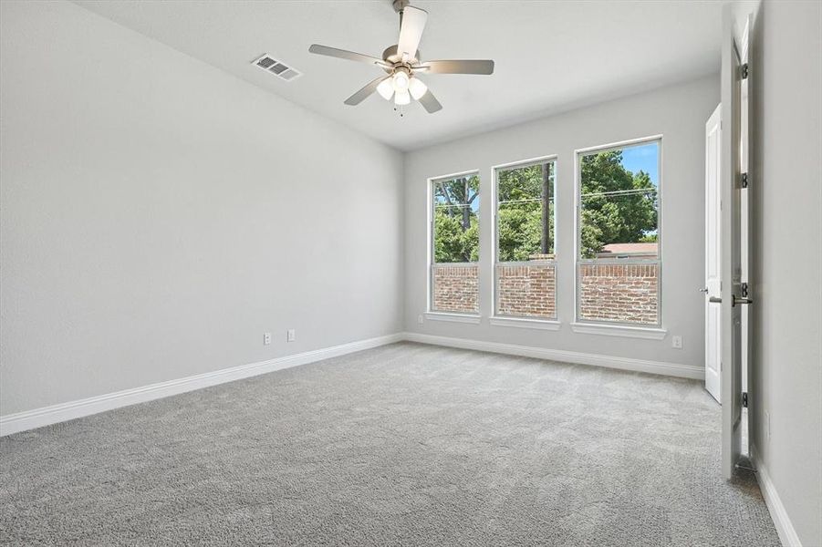 Carpeted empty room with baseboards and a ceiling fan Carpeted empty room with baseboards and a ceiling fan