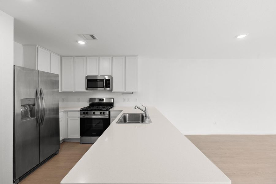 Generous peninsula offers abundant countertop space along with an integrated sink and dishwasher. Stainless steel appliances and plentiful cabinetry complete the functional kitchen layout. Generous peninsula offers abundant countertop space along with an integrated sink and dishwasher. Stainless steel appliances and plentiful cabinetry complete the functional kitchen layout.
