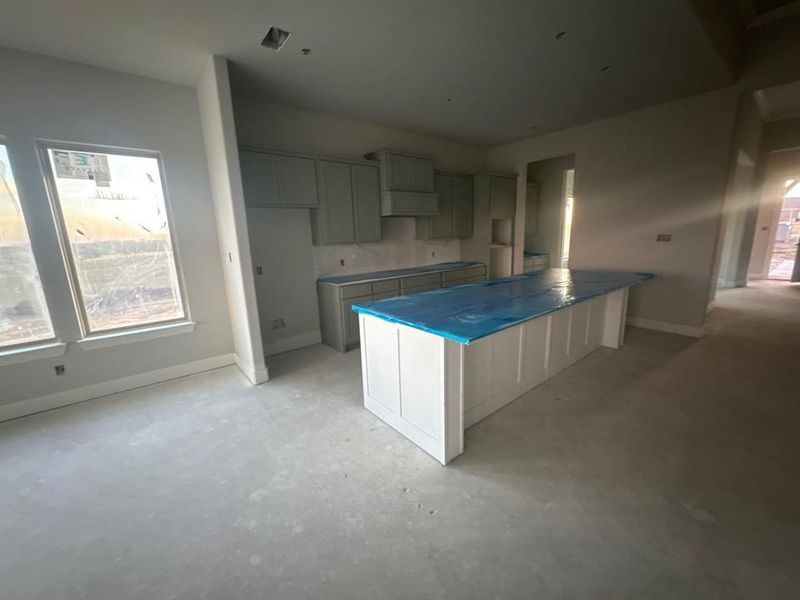 Kitchen featuring a spacious island, a kitchen breakfast bar, and unfinished concrete flooring