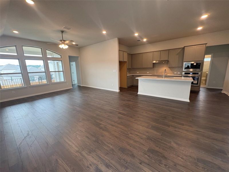 Kitchen featuring recessed lighting, appliances with stainless steel finishes, open floor plan, gray cabinets, and a kitchen island with sink