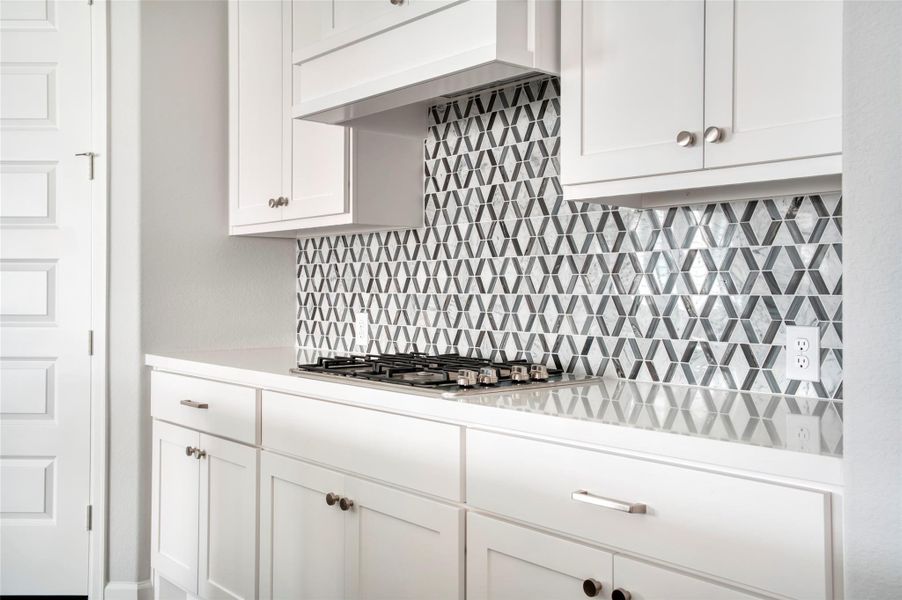 Modern kitchen with sleek white cabinetry and a stylish geometric tile backsplash. It features a built-in gas cooktop and ample storage space, creating a clean and contemporary look. Modern kitchen with sleek white cabinetry and a stylish geometric tile backsplash. It features a built-in gas cooktop and ample storage space, creating a clean and contemporary look.