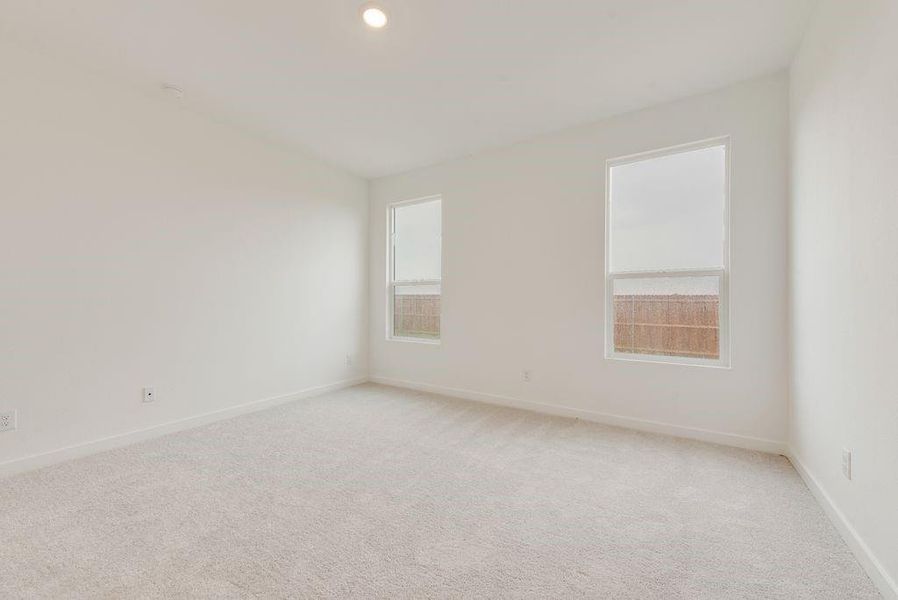 Empty room with light colored carpet and baseboards