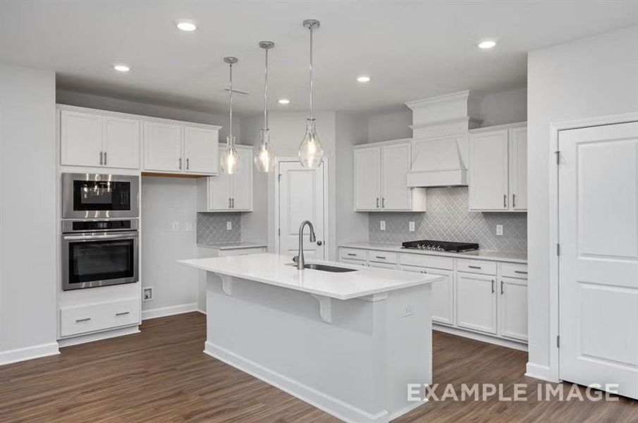 Kitchen featuring custom range hood, stainless steel appliances, white cabinets, and a sink