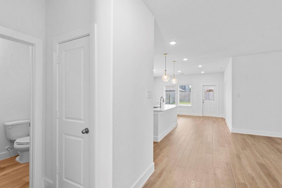 Hallway view from the entry leading toward the open kitchen and living areas, showcasing the home’s bright and airy layout. Powder Bathroom downstairs for company. Beautiful flooring throughout! Hallway view from the entry leading toward the open kitchen and living areas, showcasing the home’s bright and airy layout. Powder Bathroom downstairs for company. Beautiful flooring throughout!