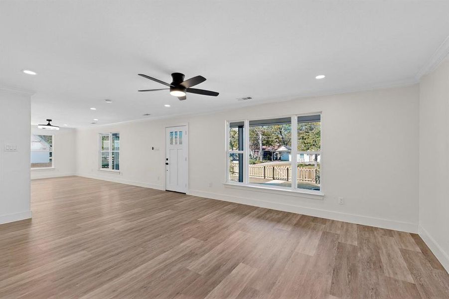 Unfurnished living room featuring crown molding, light wood-style flooring, recessed lighting, and a ceiling fan