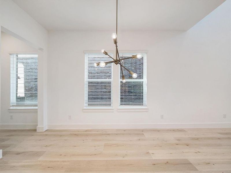 Unfurnished dining area with wood finished floors and a chandelier