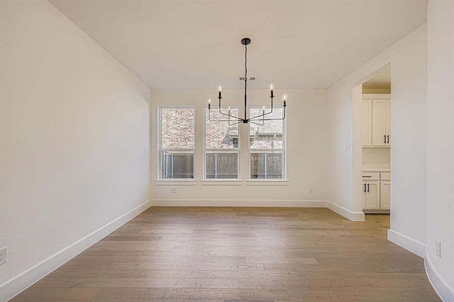 Unfurnished dining area featuring light wood-style flooring and a chandelier
