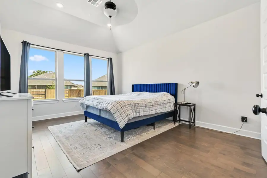 Bedroom featuring dark wood-style flooring, lofted ceiling, and a ceiling fan Bedroom featuring dark wood-style flooring, lofted ceiling, and a ceiling fan
