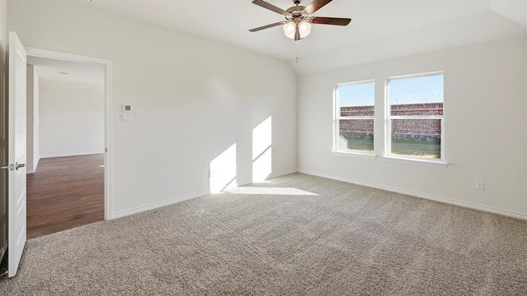 Carpeted empty room with lofted ceiling and a ceiling fan Carpeted empty room with lofted ceiling and a ceiling fan