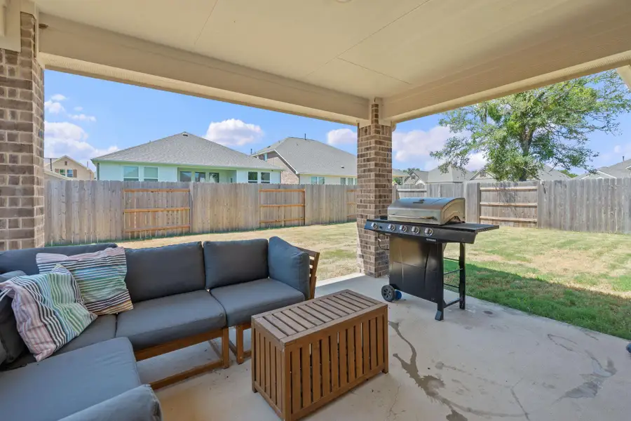 Fenced backyard featuring a patio area, area for grilling, a residential view, and an outdoor hangout area Fenced backyard featuring a patio area, area for grilling, a residential view, and an outdoor hangout area