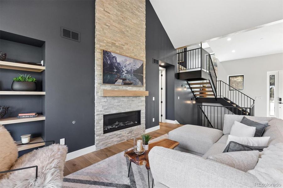Cozy Living area with floor to ceiling stone detail, gas fireplace, hard wood floors, and built-in shelving Cozy Living area with floor to ceiling stone detail, gas fireplace, hard wood floors, and built-in shelving